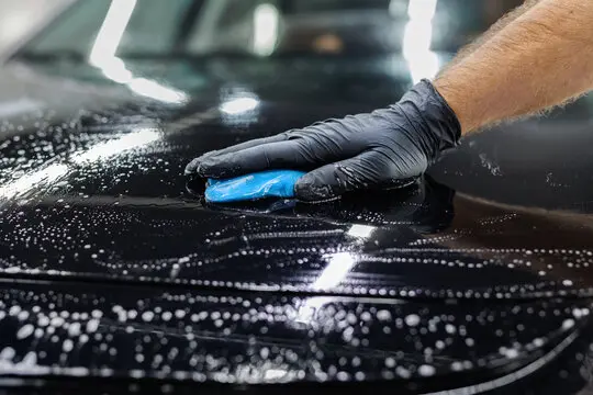 black vehicle getting a clay bar treatment before paint correction and ceramic coating in kansas city