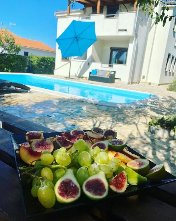 A smiling young man with crossed arms, wearing a plaid shirt and white t-shirt, poses against a dark background.