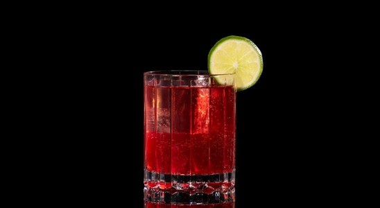A closeup of a Pomegranate Mule drink against a dark background.