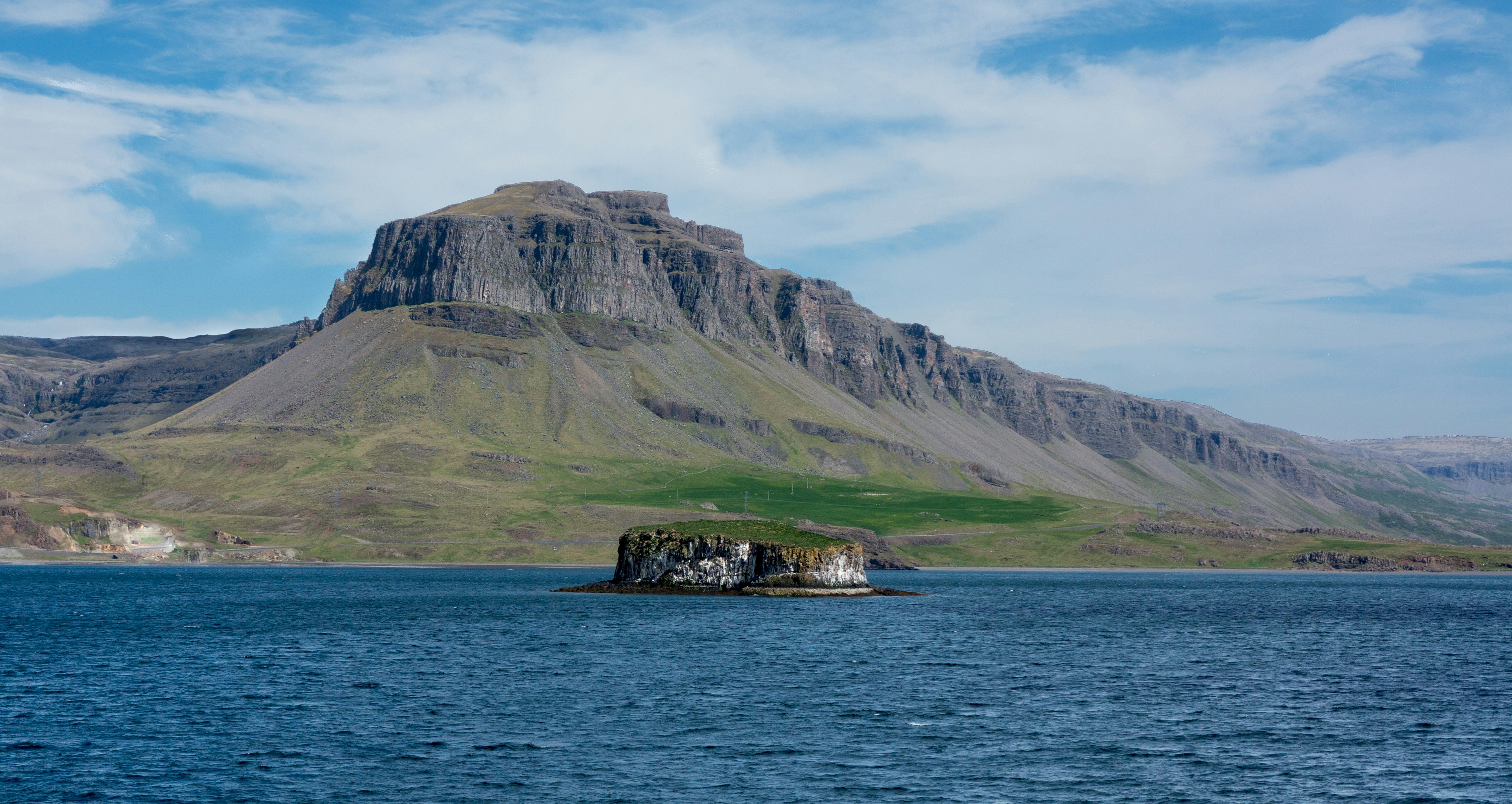 Steep-sided Geirshólmi island rising from the waters of Hvalfjörður, Iceland.