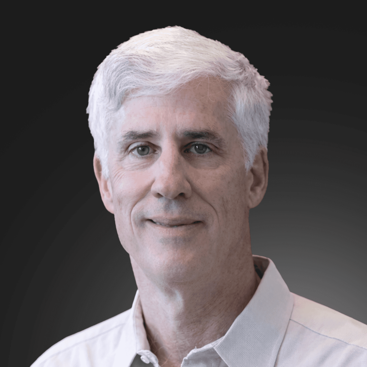 A young man with dark hair smiles at the camera, set against a modern indoor background.