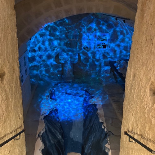 A cave-like room with stone walls, subtle blue lighting, and a water feature resembling a small indoor river.