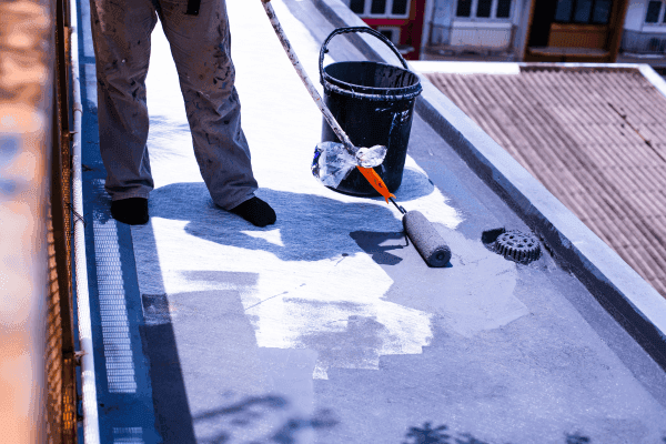 專業師傅於香港天台進行防水工程,使用滾筒塗刷隔熱防水塗層,解決屋頂漏水維修及天台地台翻新問題。