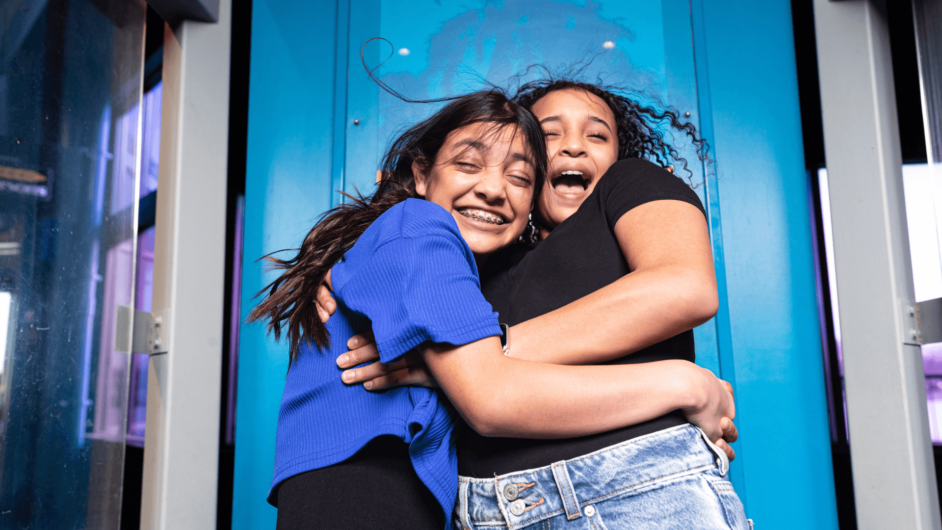 Two young girls smile and laugh as they experience hurricane force winds.