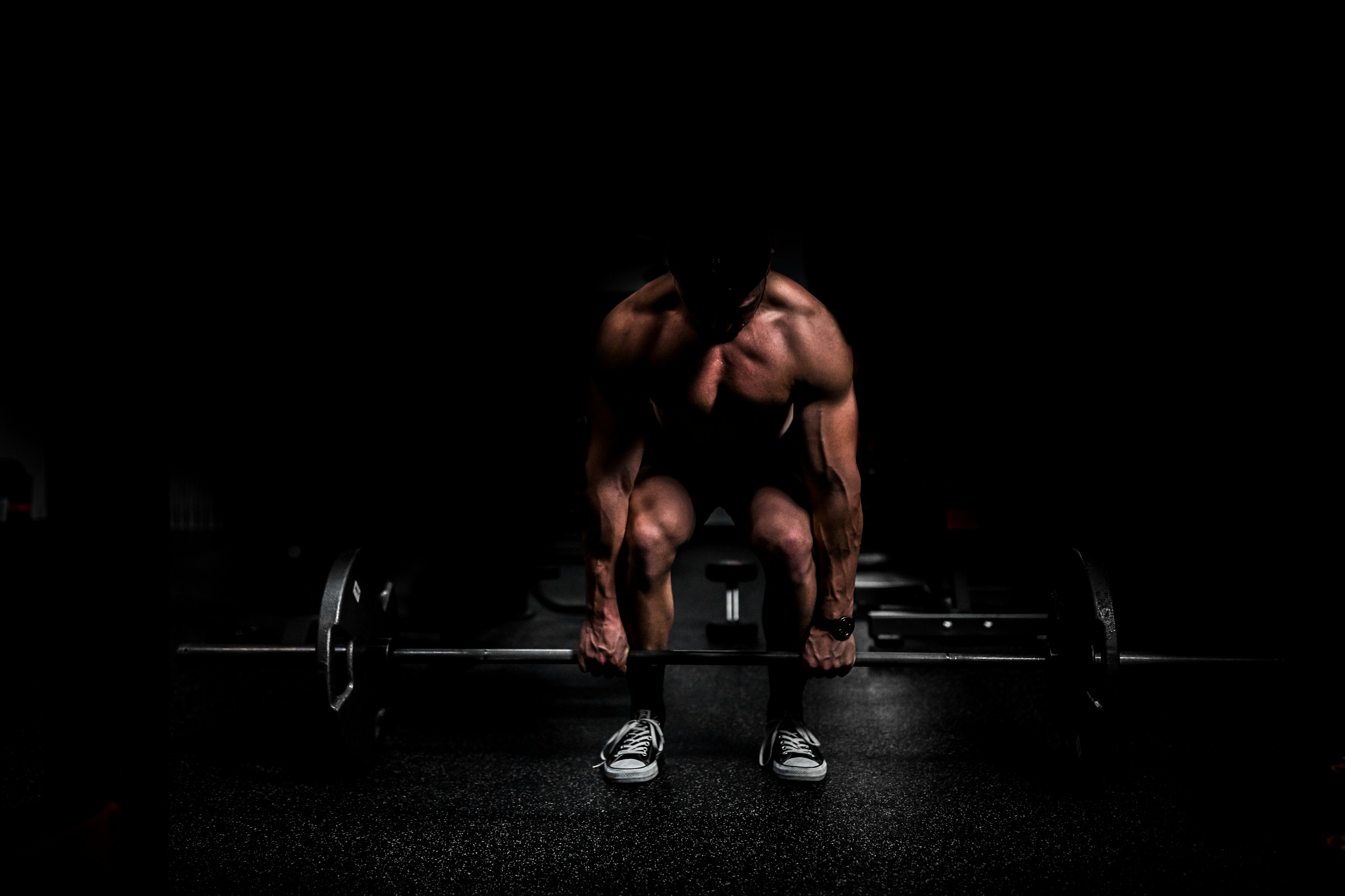 A high-contrast, professional cinematic shot of an athlete training in a dark, atmospheric gym setting with dramatic lighting.