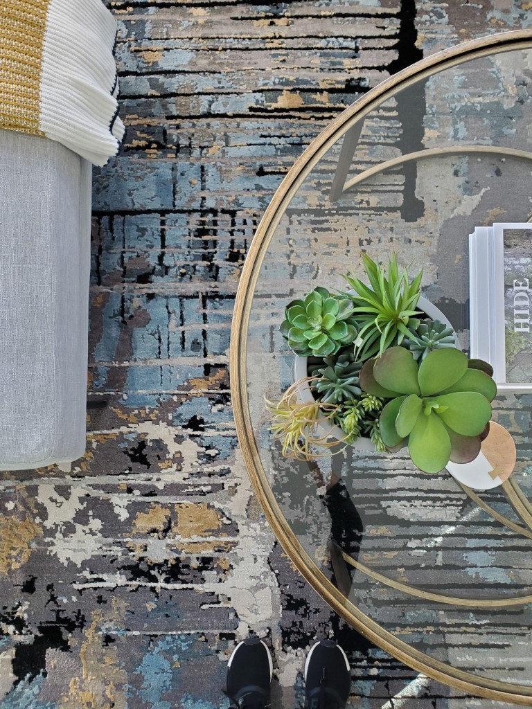 Image of Glass table with gold frame, succulents, and modern furniture on rustic floor, KHD Homes interior design.