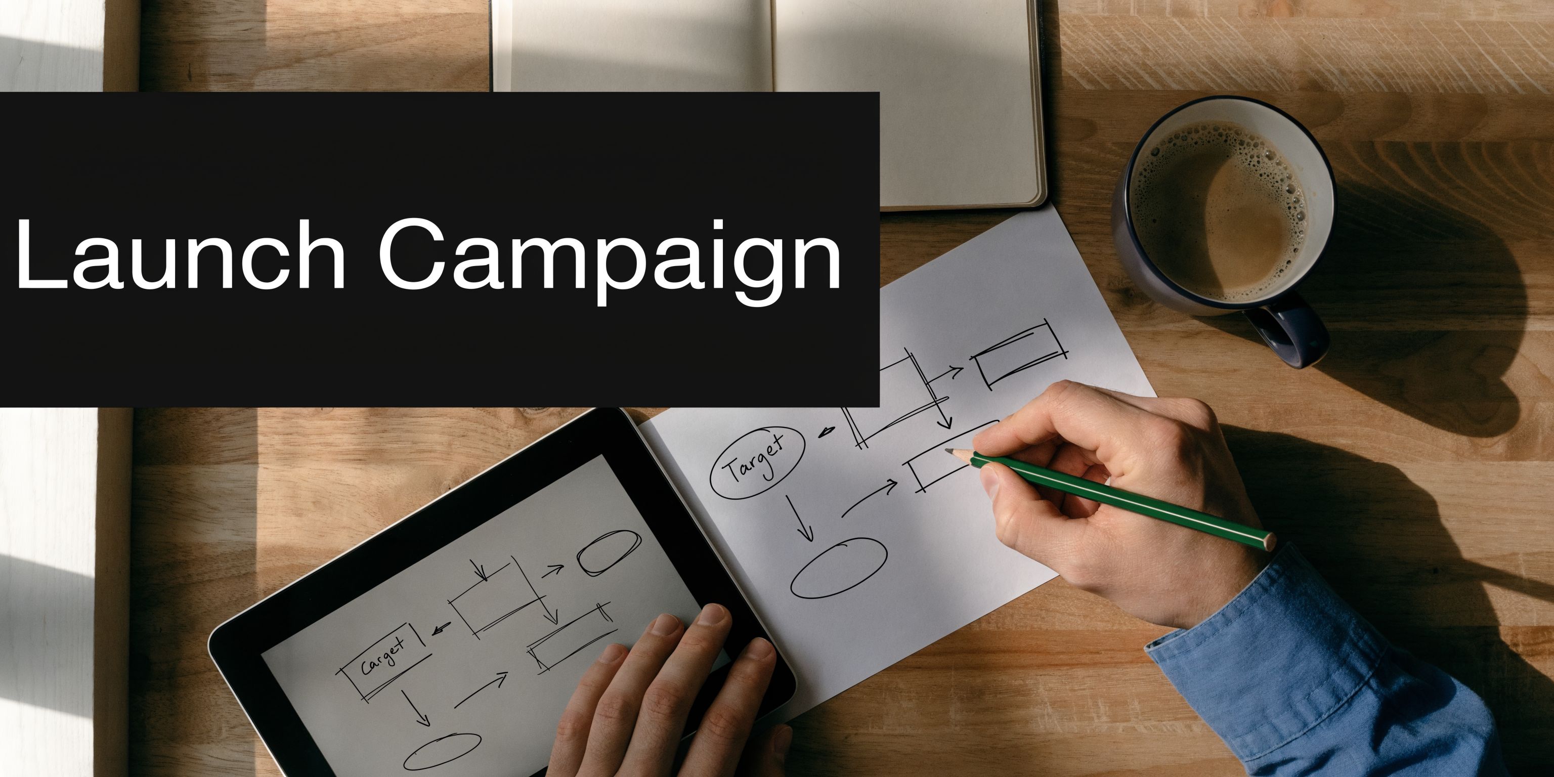 A person drawing a business flowchart on paper while looking at a tablet on a desk.