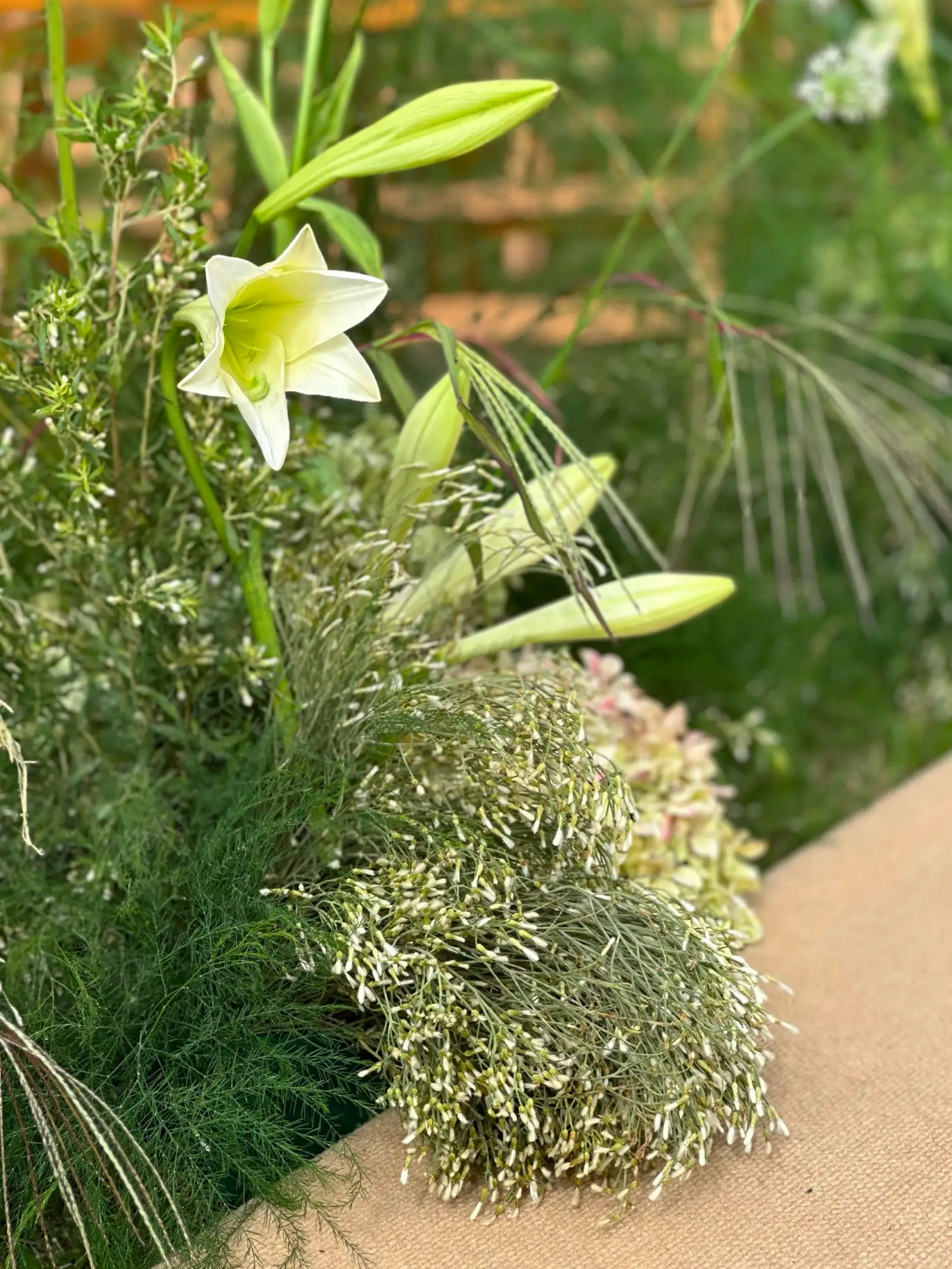 Detalle de lirio blanco entre follajes y flores secas para diseñadores florales que valoran lo natural y la elegancia sutil.