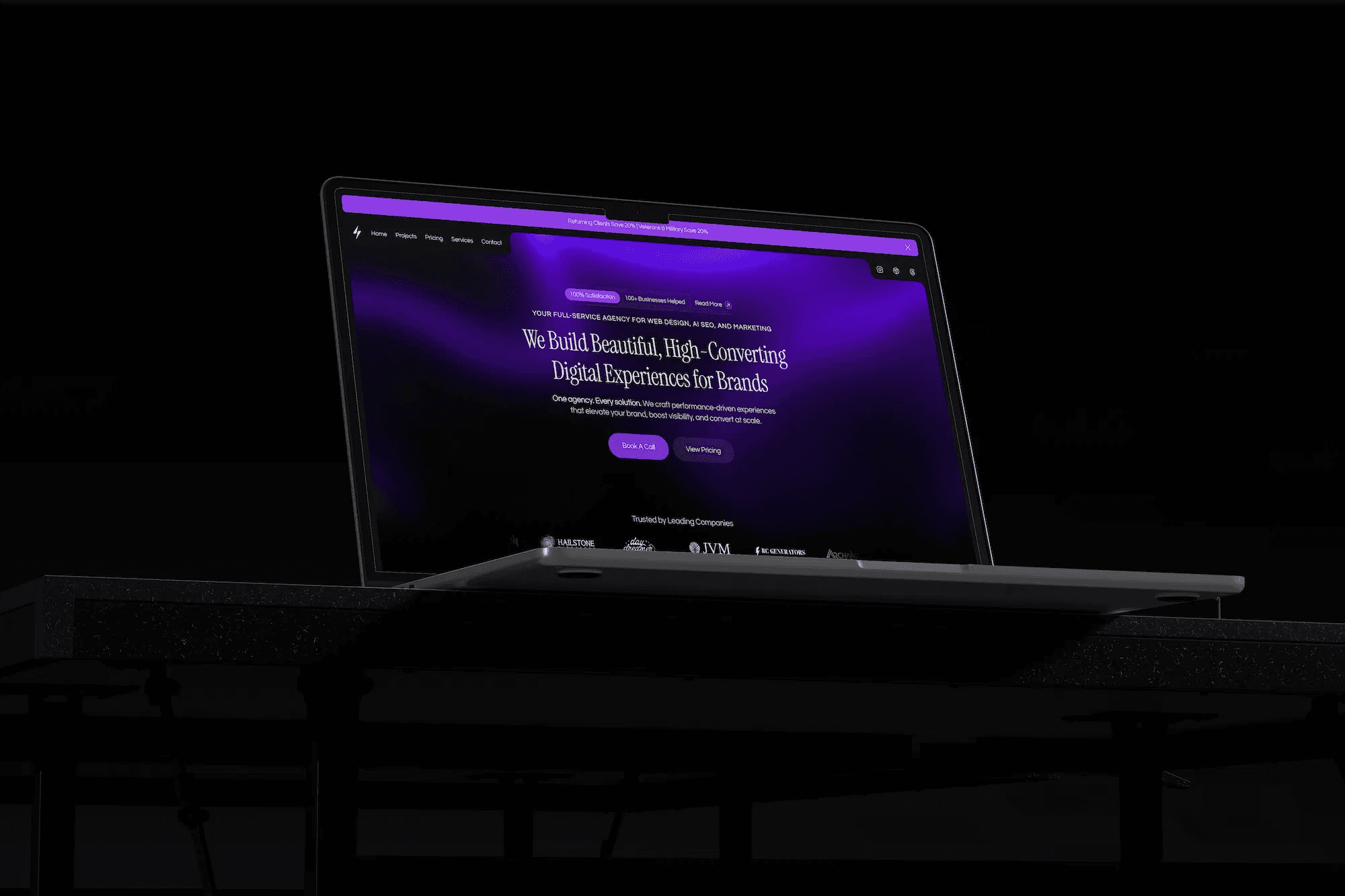 a black room with a laptop on a desk showing Nextus Digital Solutions' website