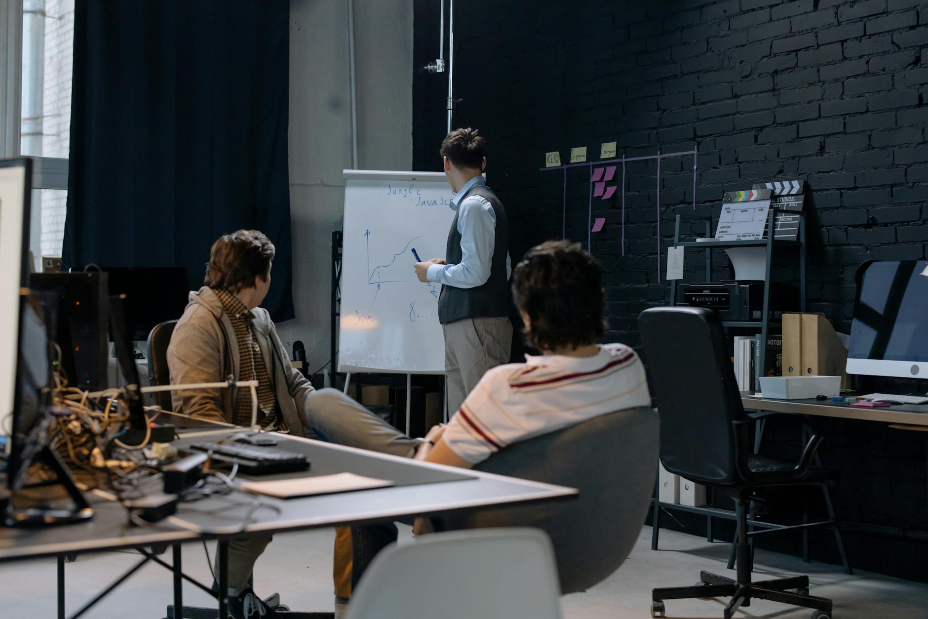 A student writes on a small, handheld individual dry-erase lapboard while sitting on a colorful rug.