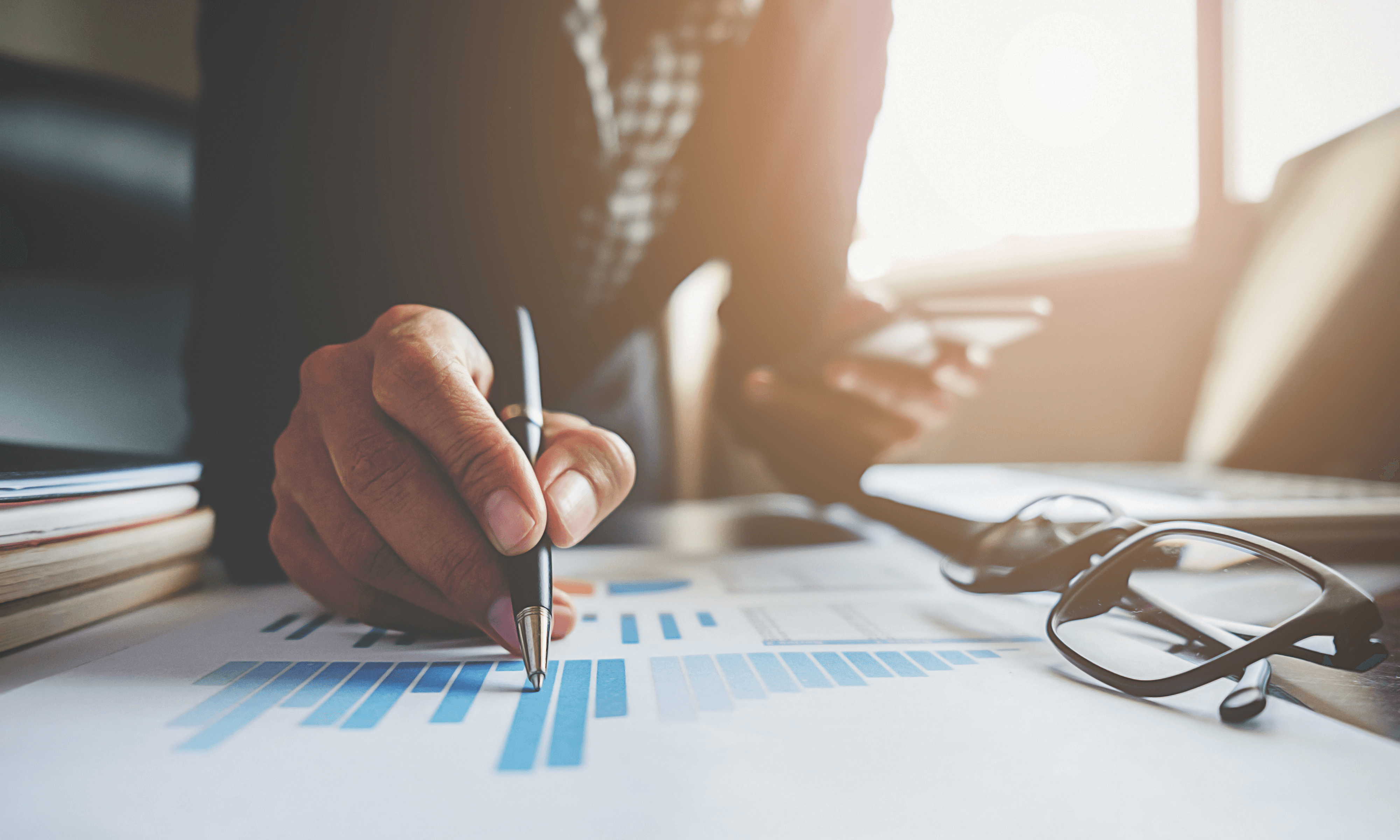 Close-up of a person analysing data charts and using a smartphone, representing data-driven decision-making and business insights.