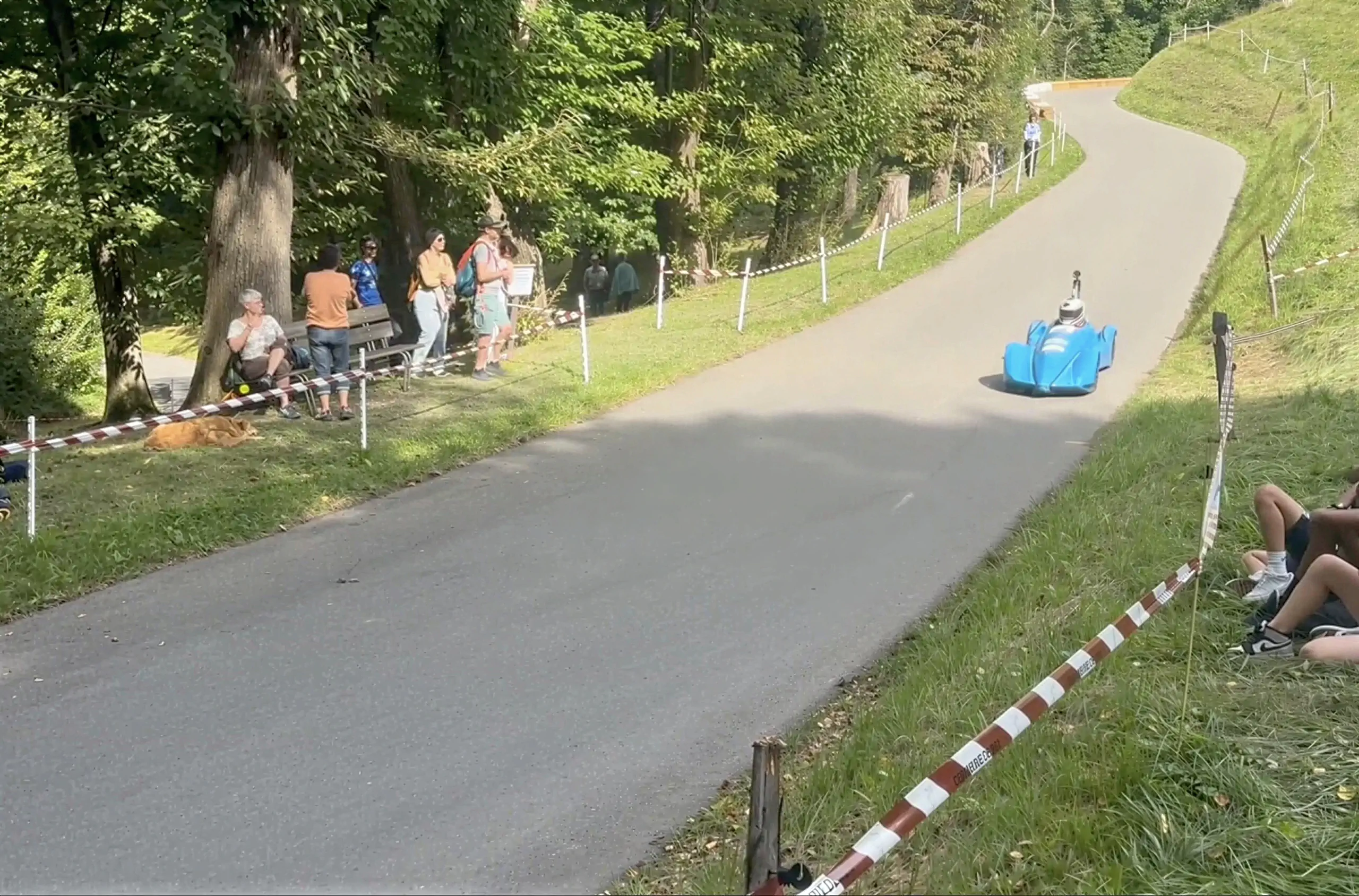 Route sinueuse en forêt lors d'une course de speed down avec spectateurs au bord de la piste