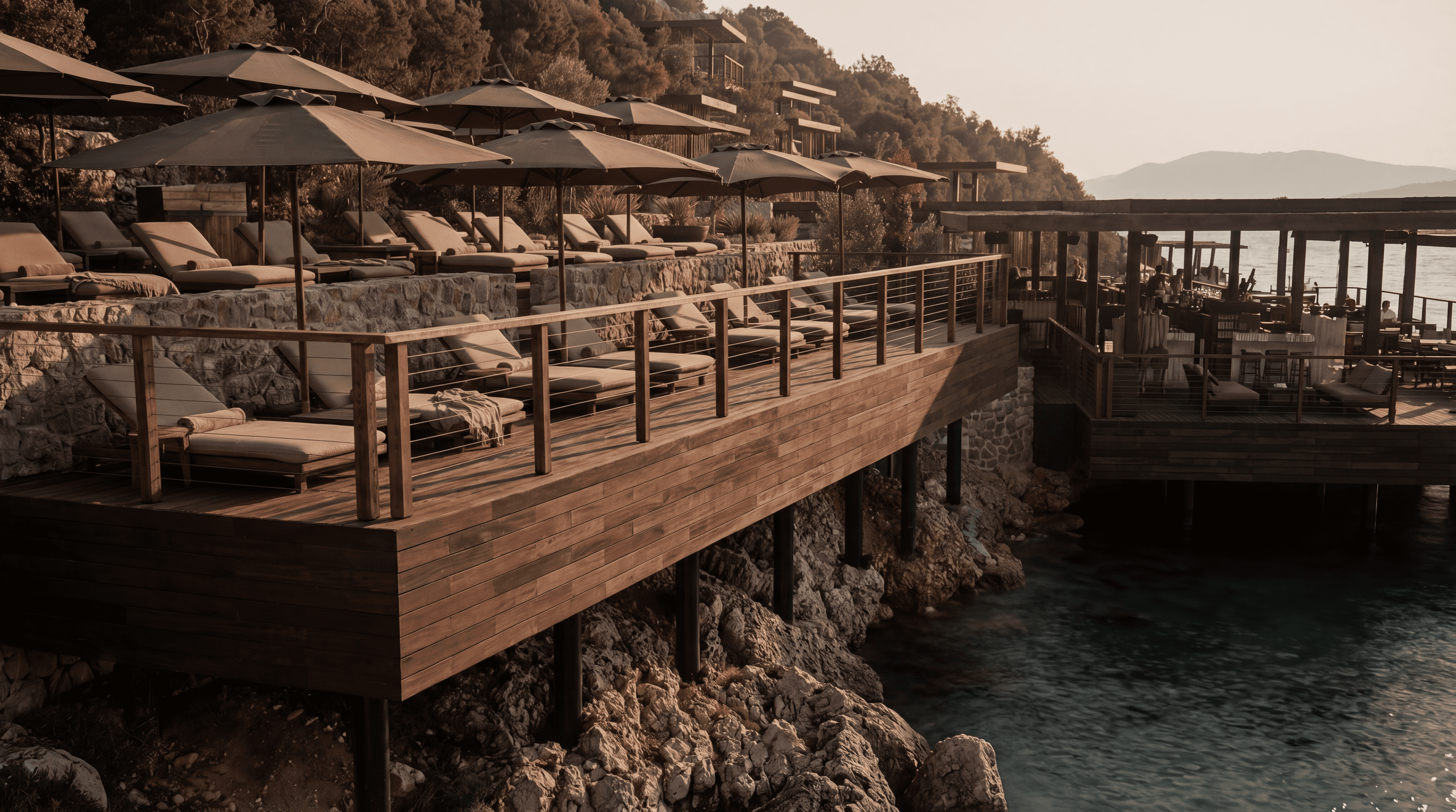 Wooden deck and stone architecture over turquoise water at Scorpios Beach Club Bodrum, Cennet Koyu