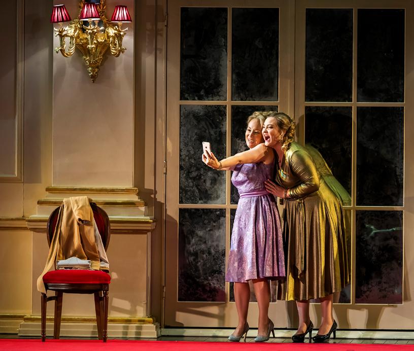 Two women taking a joyful selfie in an elegant interior during Cosi fan tutte.