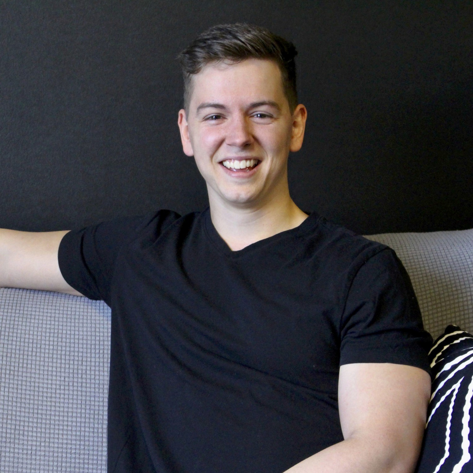 A smiling young man sitting on a couch.
