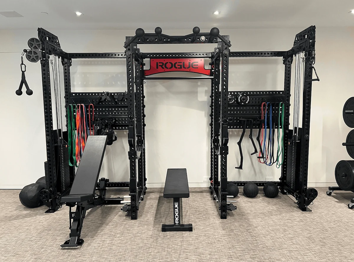 Rogue power rack with dual cable system and bench in a luxury custom home gym build in Canada.