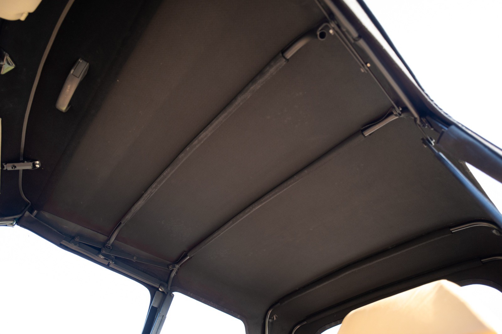 Interior view showing the ceiling of a vehicle, featuring a dark surface and light filtering through.