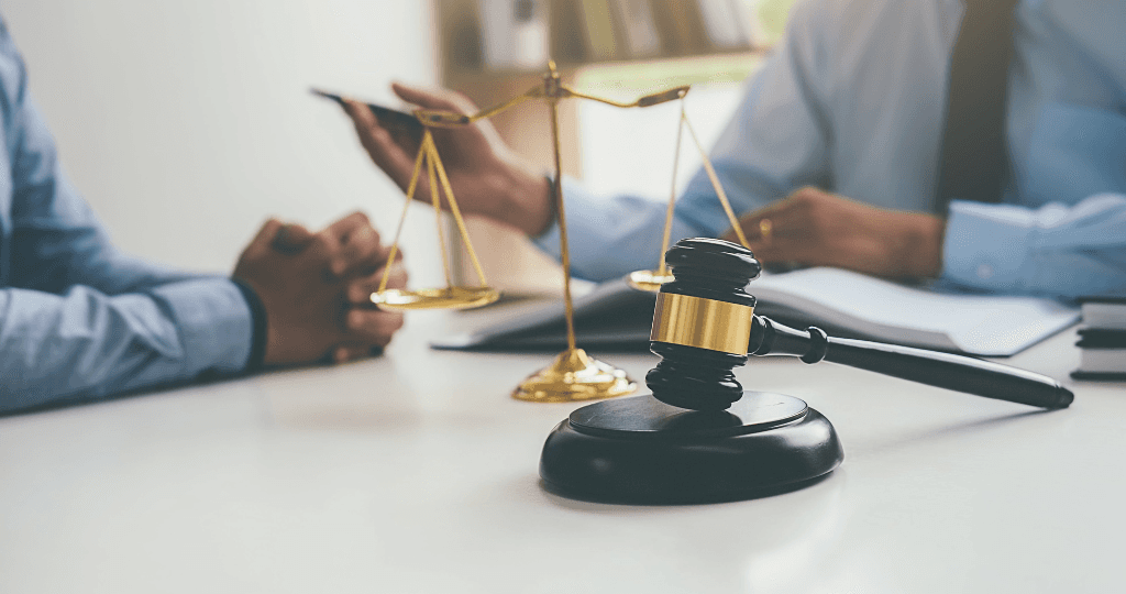 Close-up of a gavel, scales of justice, and two lawyers discussing legal billing strategies.