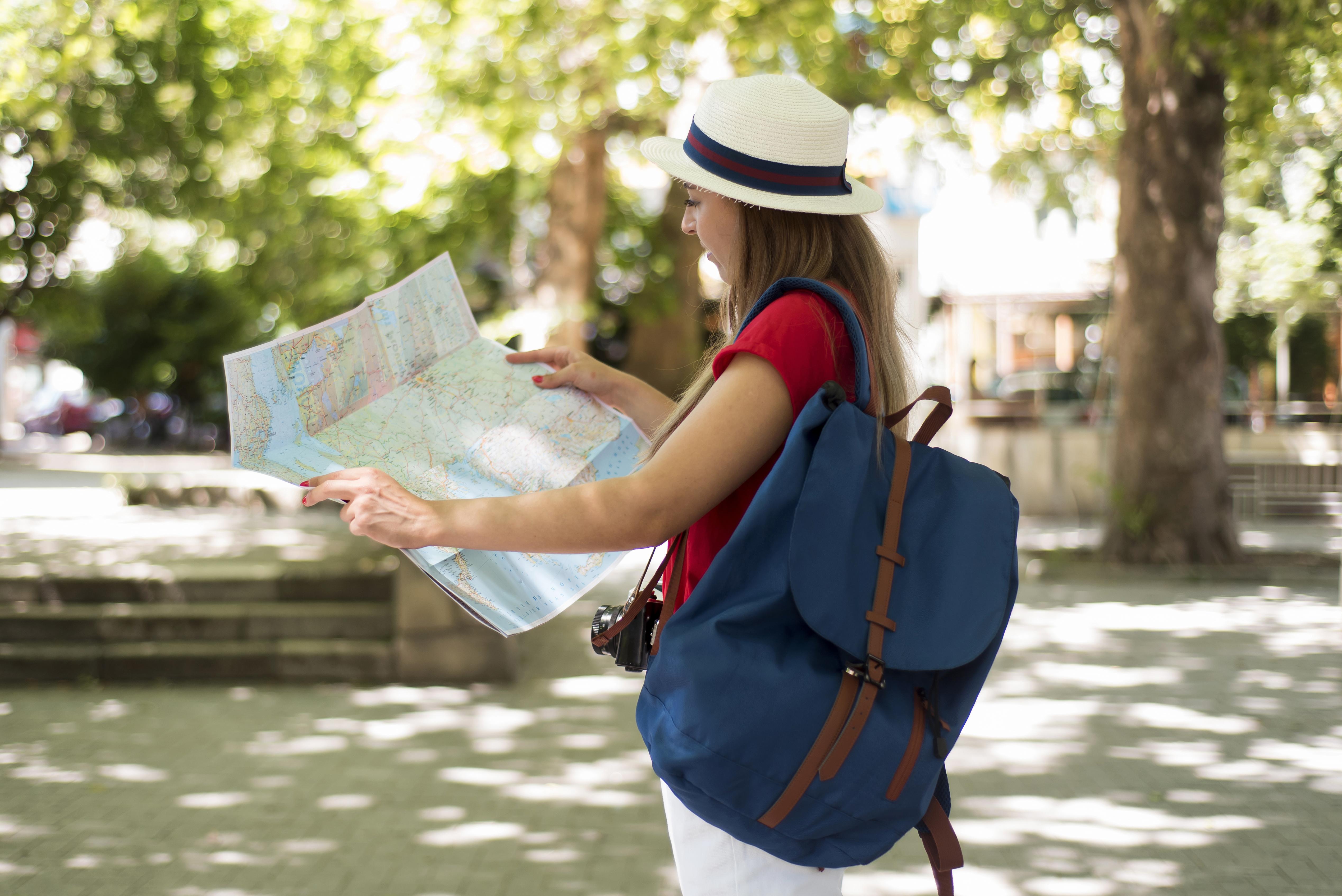 Women with a white hat and an map in her hands by traveling a city
