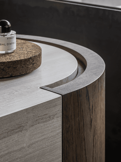 Close-up van een gebogen moderne tafel met gladde houtnerf en een stenen oppervlak, die verfijnd interieurvakmanschap laat zien