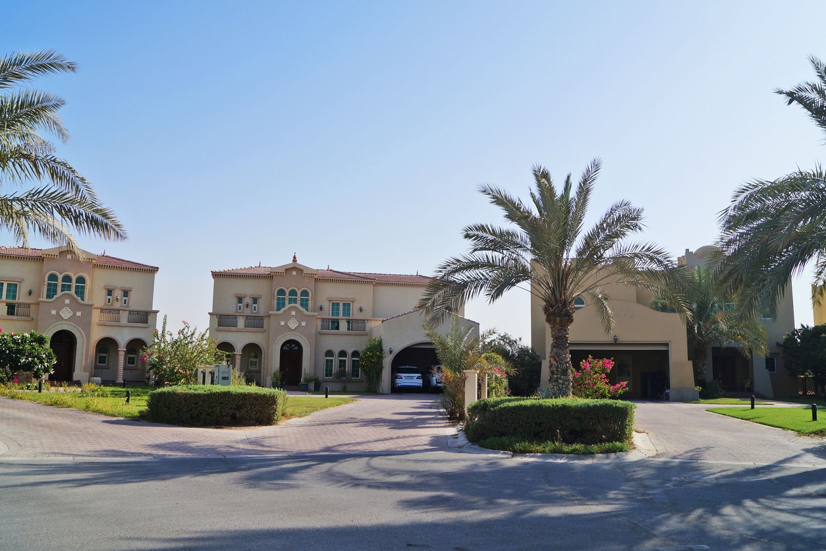 A luxurious driveway leads to elegant houses surrounded by palm trees in the upscale Jumeirah Islands community.