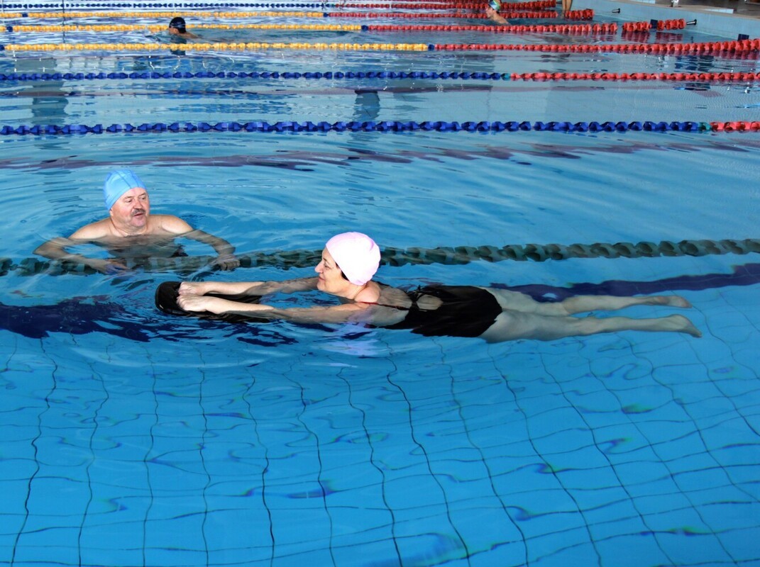 middle-aged woman using a kickboard to do swimming workouts to lose weight for beginners