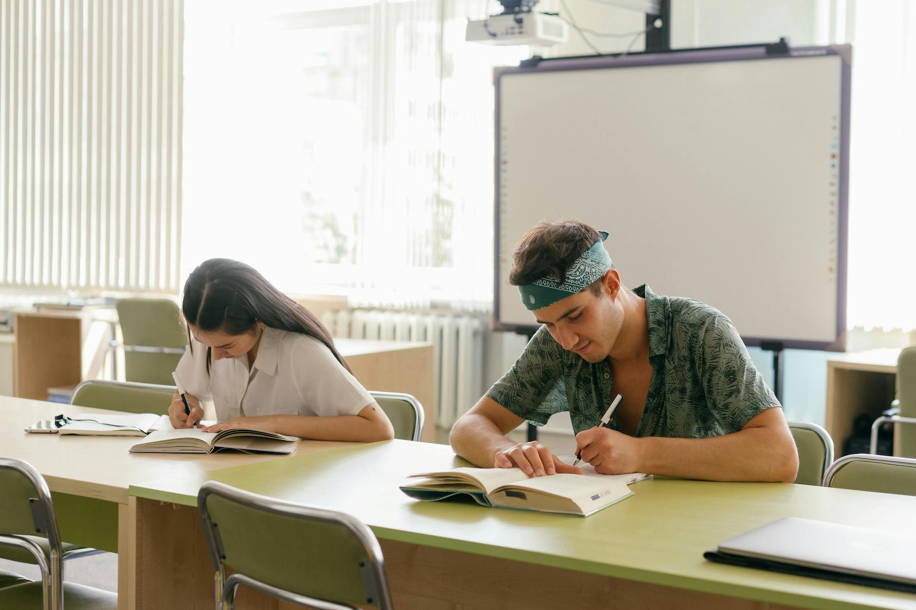 A teacher and teenager sitting side-by-side writing specific academic goals in a spiral-bound planner.
