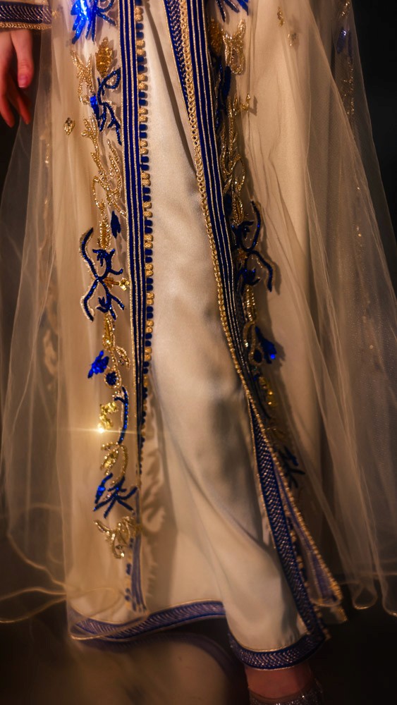 Ivory Moroccan caftan with deep blue embroidery, handcrafted couture piece combining Bahrain atelier and Moroccan artisans