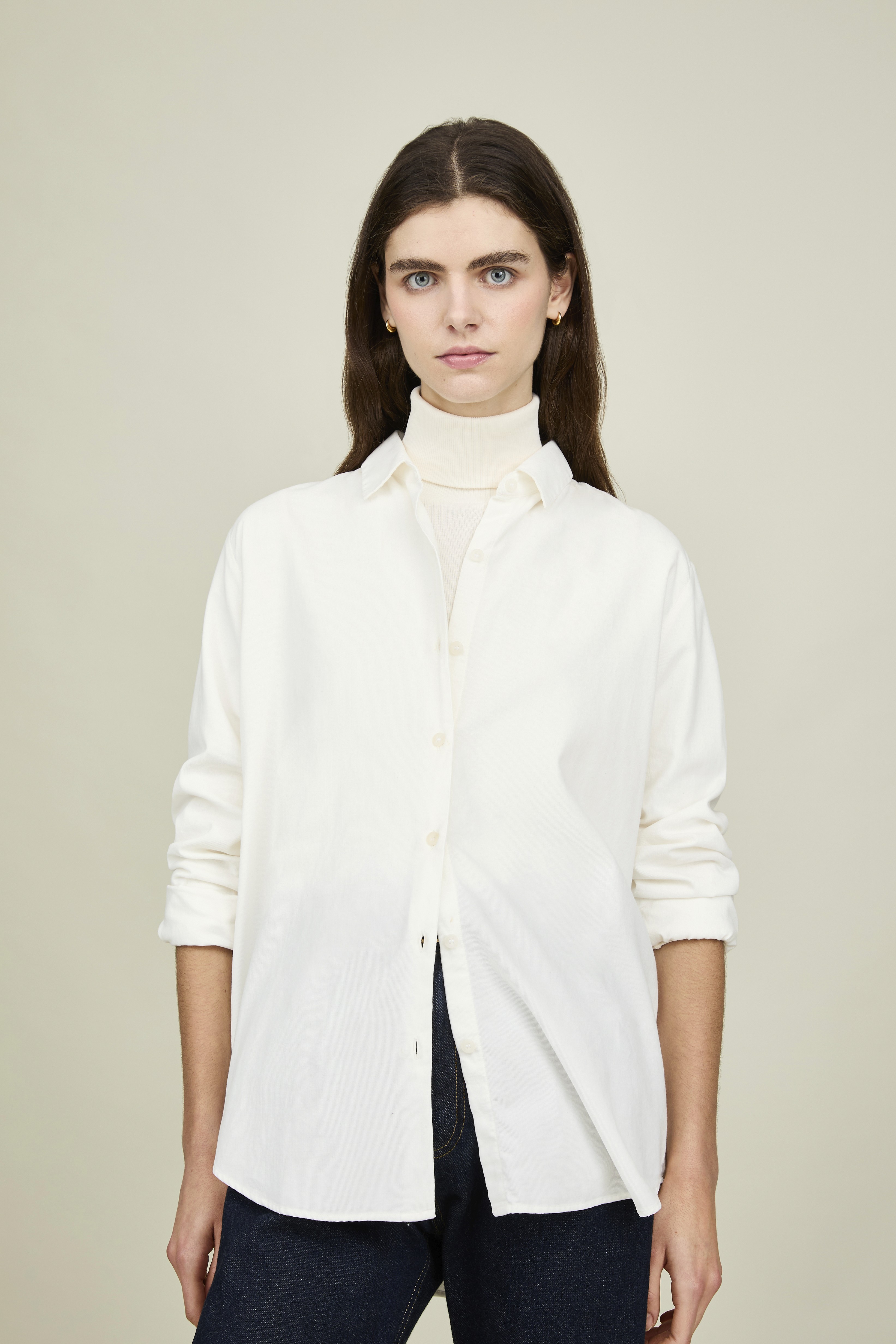 Dans le lookbook de la marque Sunspel, une femme porte une chemise blanche sur un col roulé de même couleur