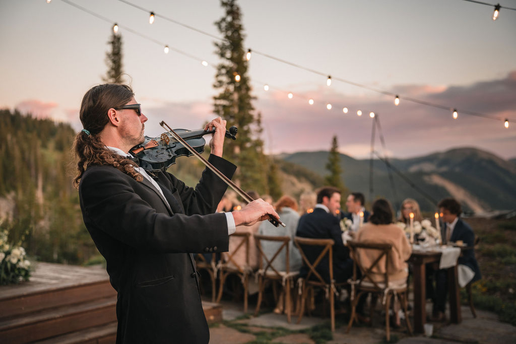 Live violin performance during reception at Smith Cabin Aspen wedding with guests dining outdoors