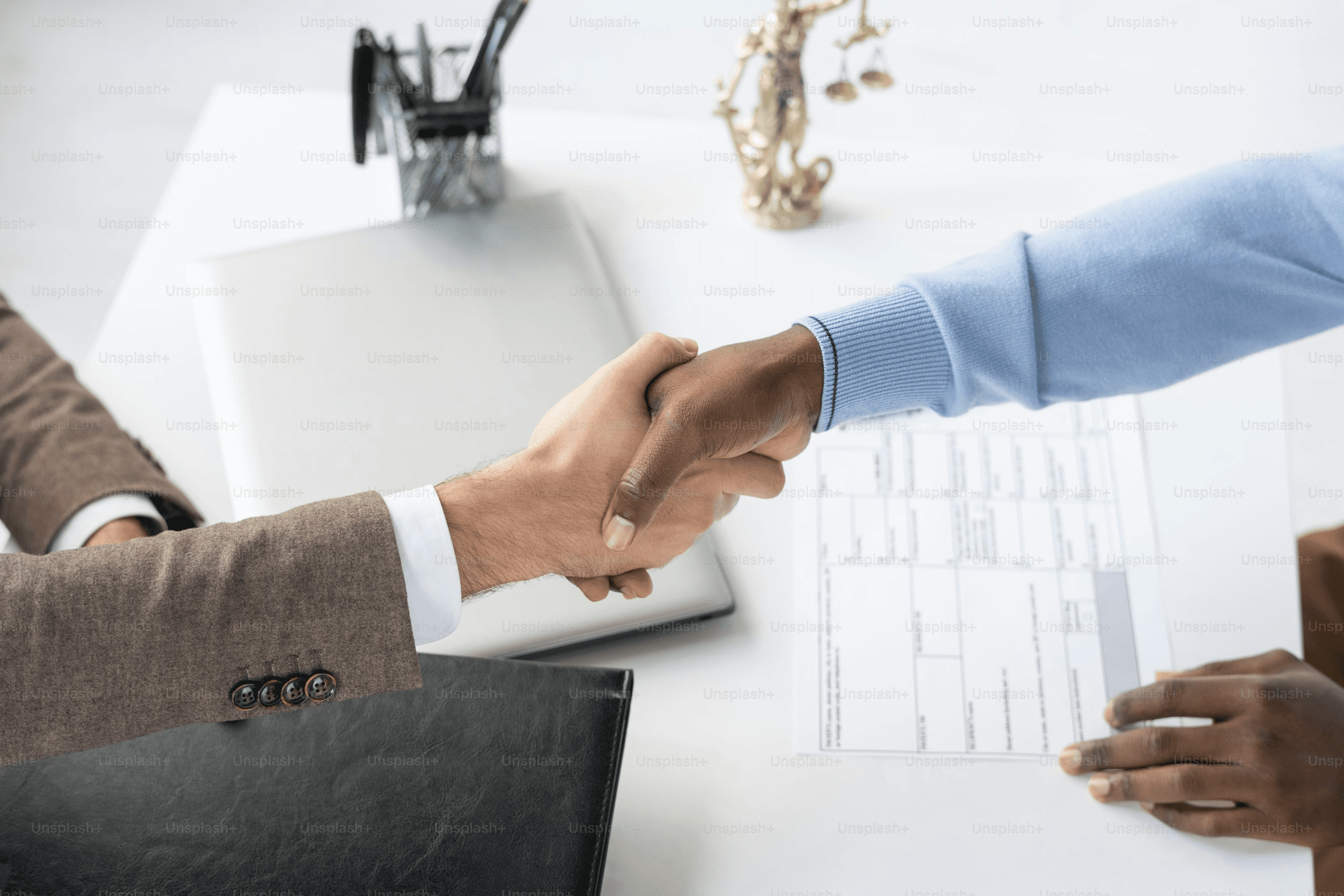 Lawyer and client shaking hands over documents during a consultation