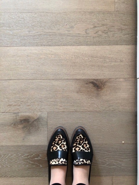 Image of KHD Homes showcases stylish flooring with a person's feet wearing leopard print loafers on wooden planks.