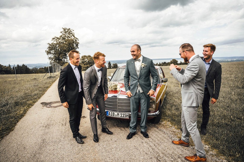 Bräutigam mit Freunden vor Oldtimer während Hochzeit auf der Seiseralm am Chiemsee