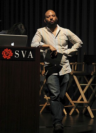 portrait of a man resting his arm on a stand with a spotlight on him