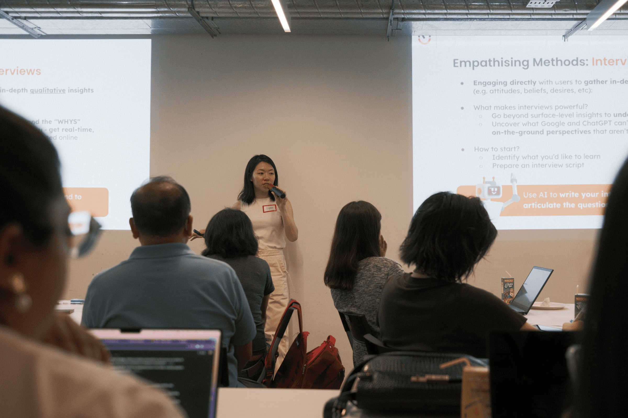 An eye-level shot of Lynn, our presenter of the workshop, talking to the participants of the AI x Design Thinking Workshop.