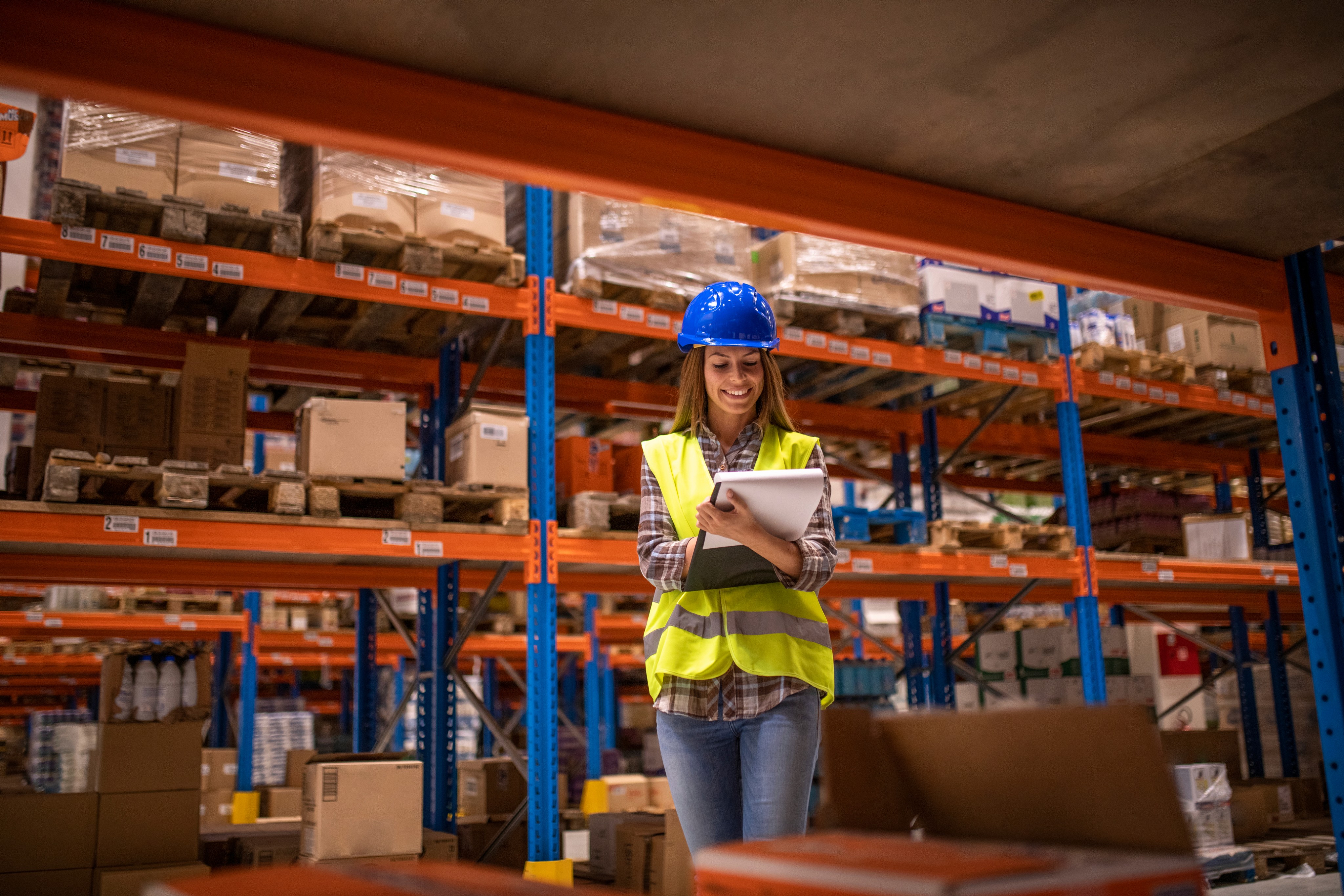 Woman logistics manager using a tablet in a busy warehouse.