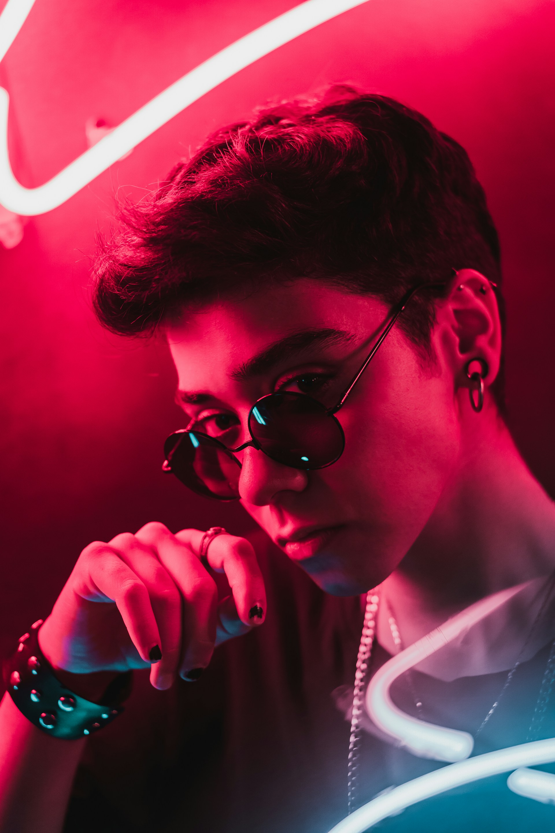 Person with round sunglasses lit by red neon.