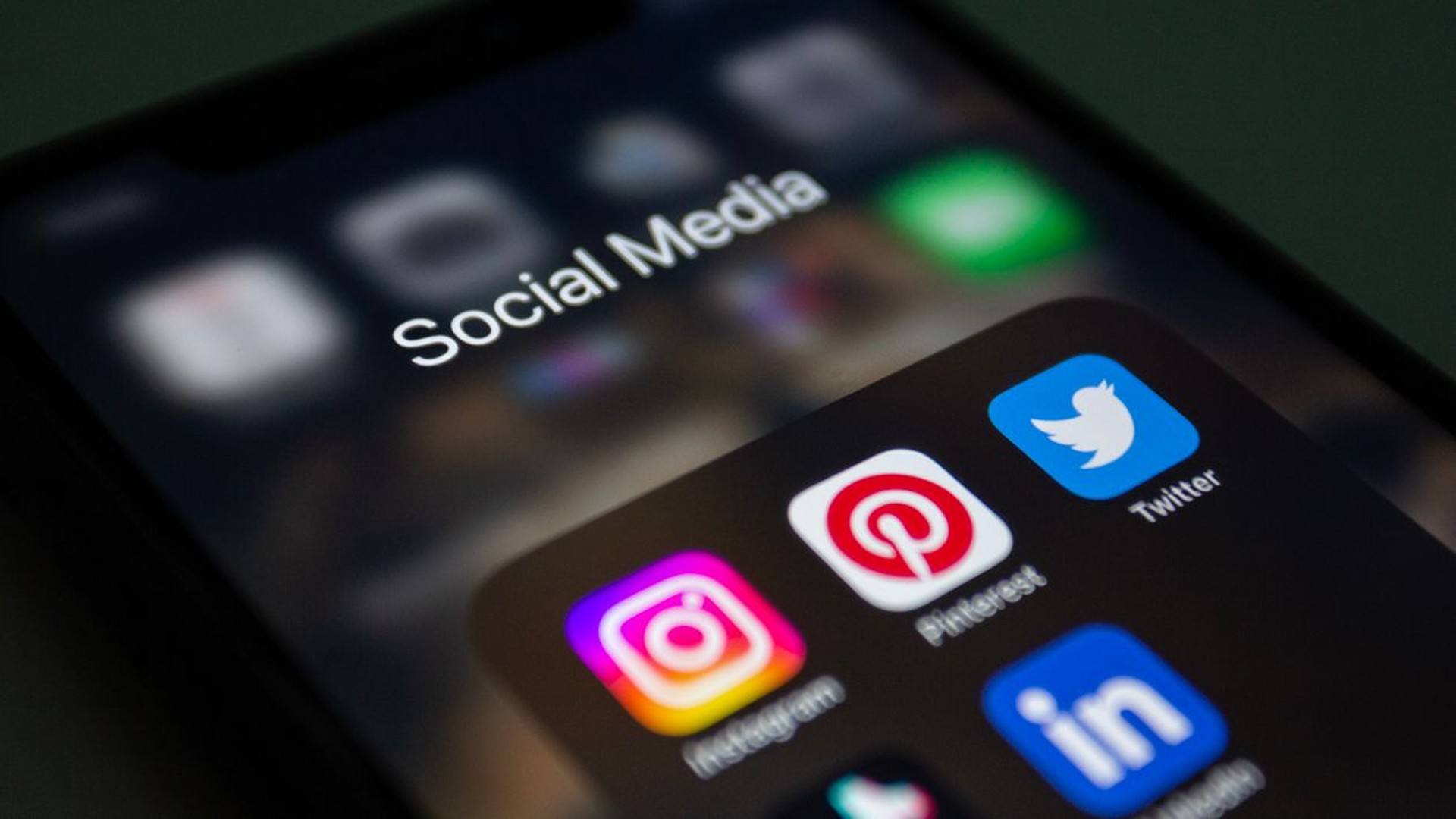 Close-up of a smartphone social media folder with Instagram, Pinterest, Twitter, and LinkedIn apps, showing common digital distractions and the need for digital detox, screen time control, productivity, and digital minimalism with minimalist phone.