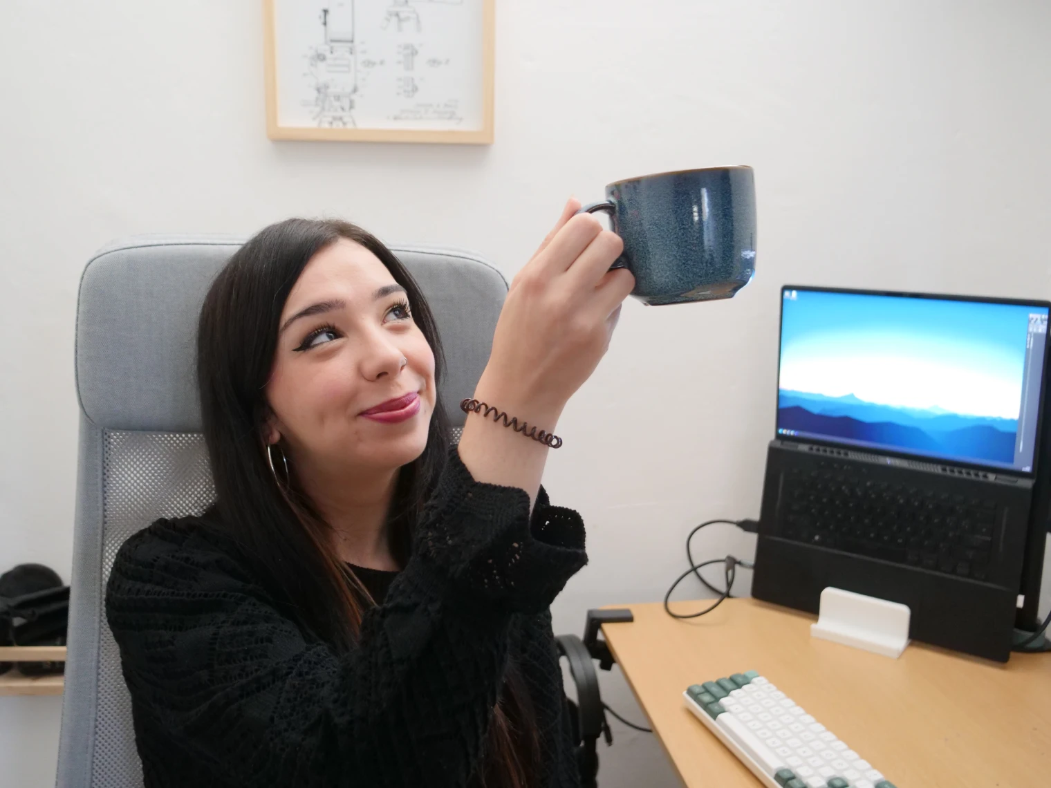 Lorena working remotely on her desk, raising a mug