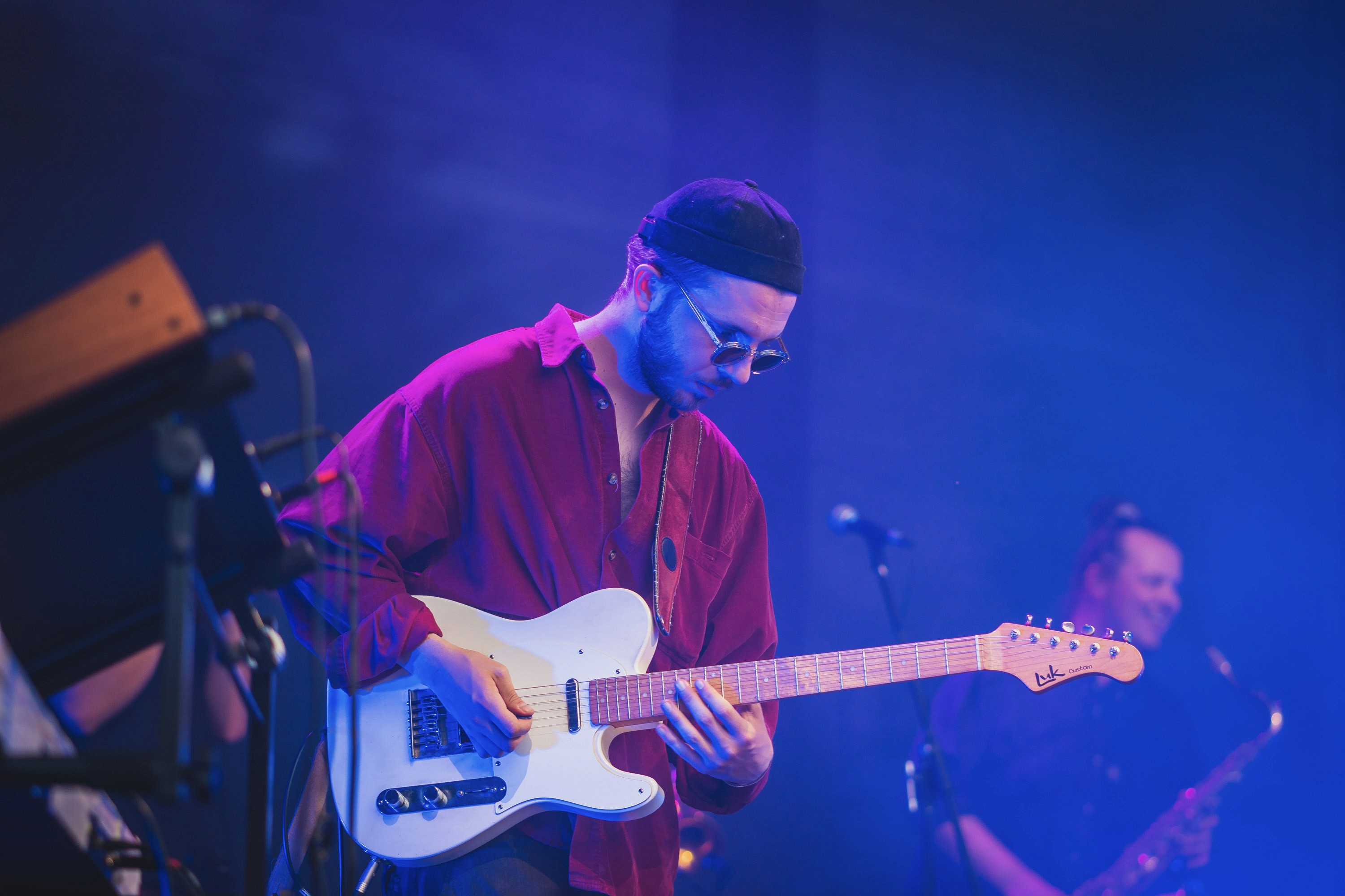 Musician performing with electric guitar under blue and purple stage lighting effects