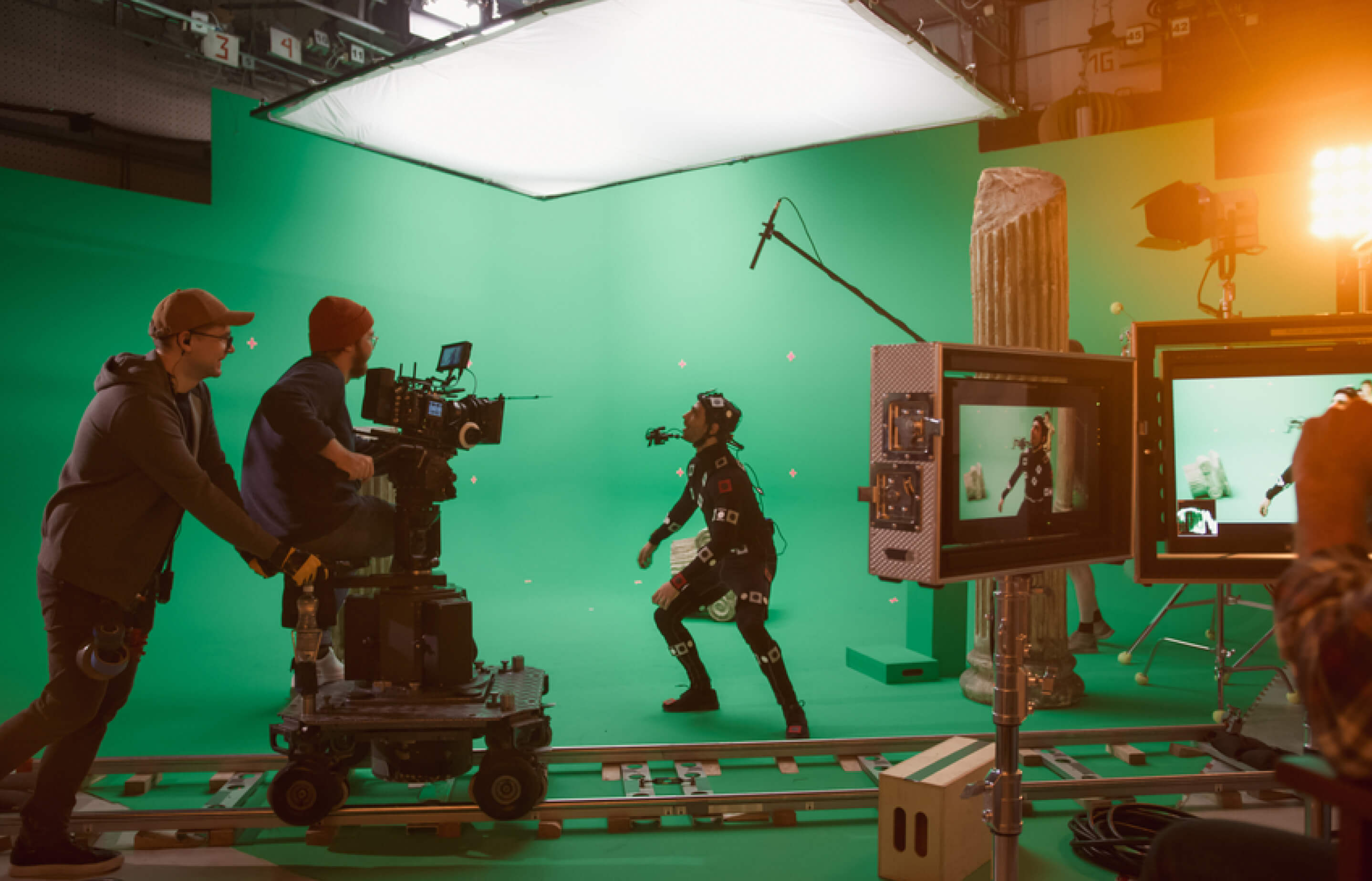 A film crew operates on a green screen set, capturing a scene with cameras and lighting equipment.