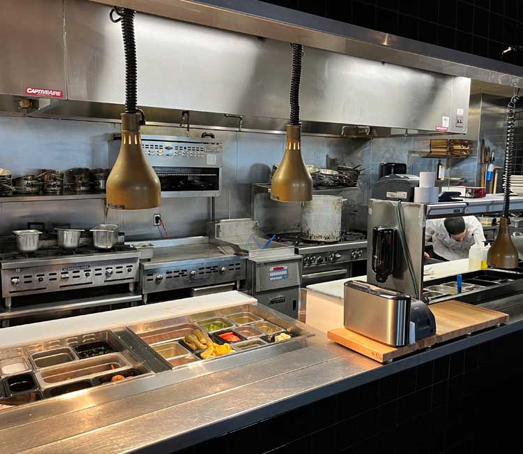 A man fixing a refrigirator on his knee in a traditional american kitchen