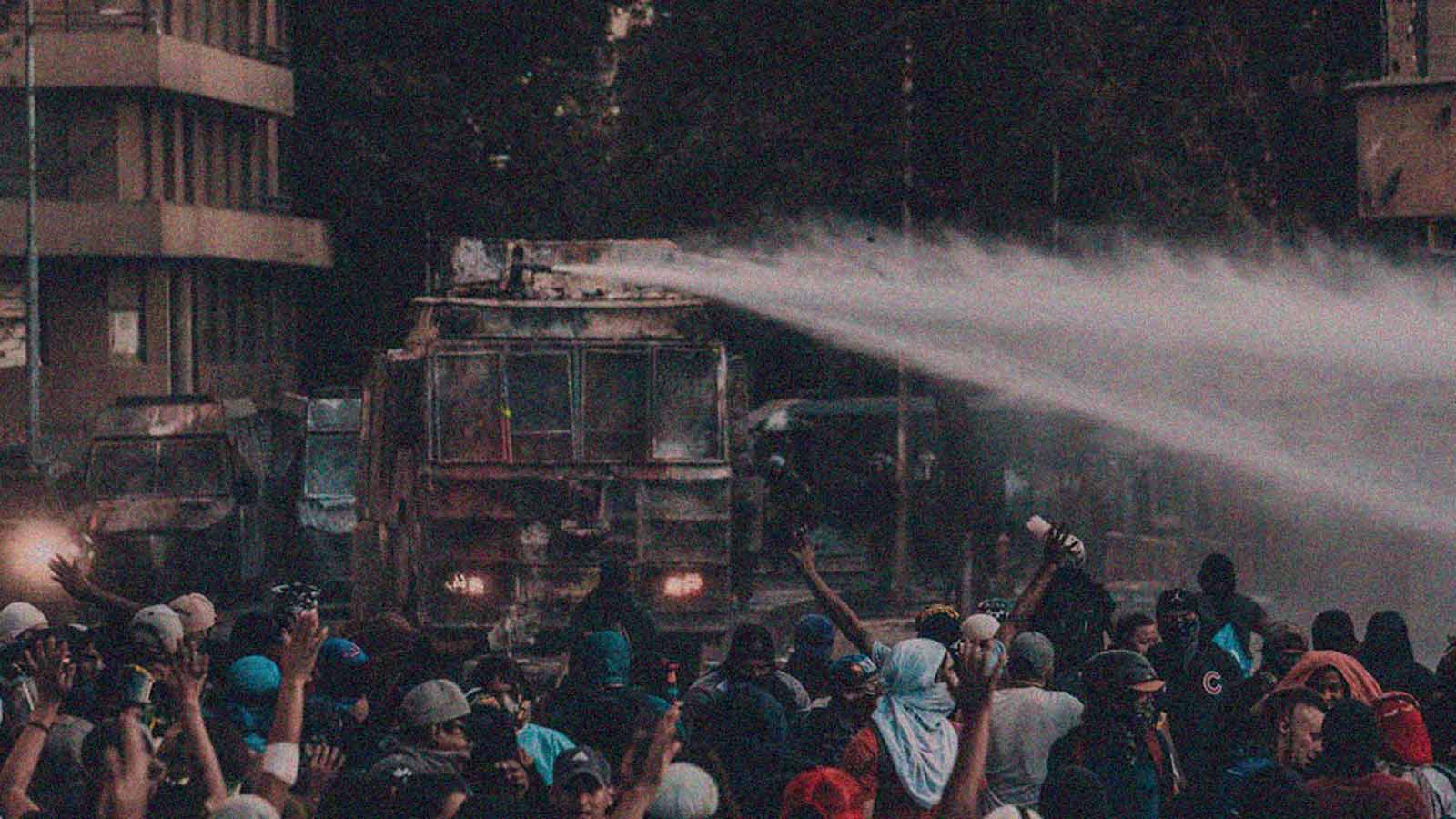 Foto de un carro lanza aguas en una protesta en la columna de opinión Entre decir y hacer de IdeaPaís.