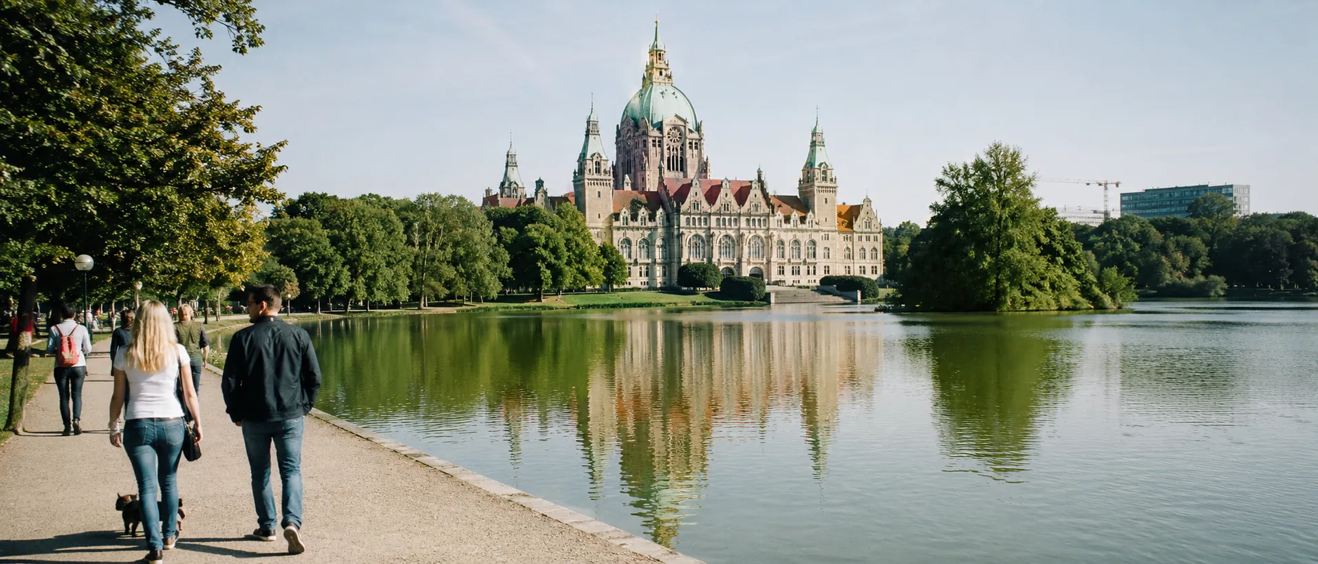 Maschsee in Hannover mit Spaziergängern, Wasserreflexion und Neuem Rathaus im Hintergrund