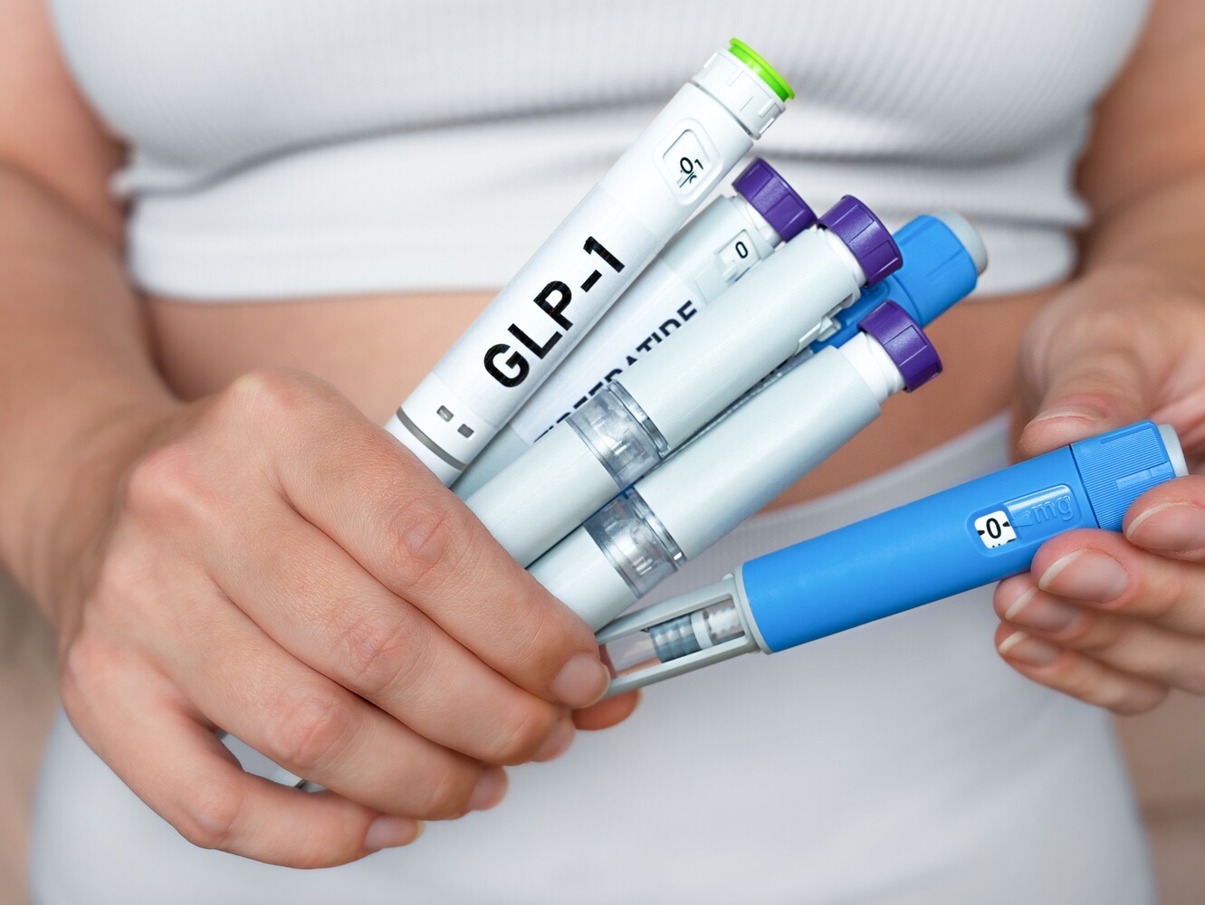 woman holding a variety of weight loss injectables to showcase different options