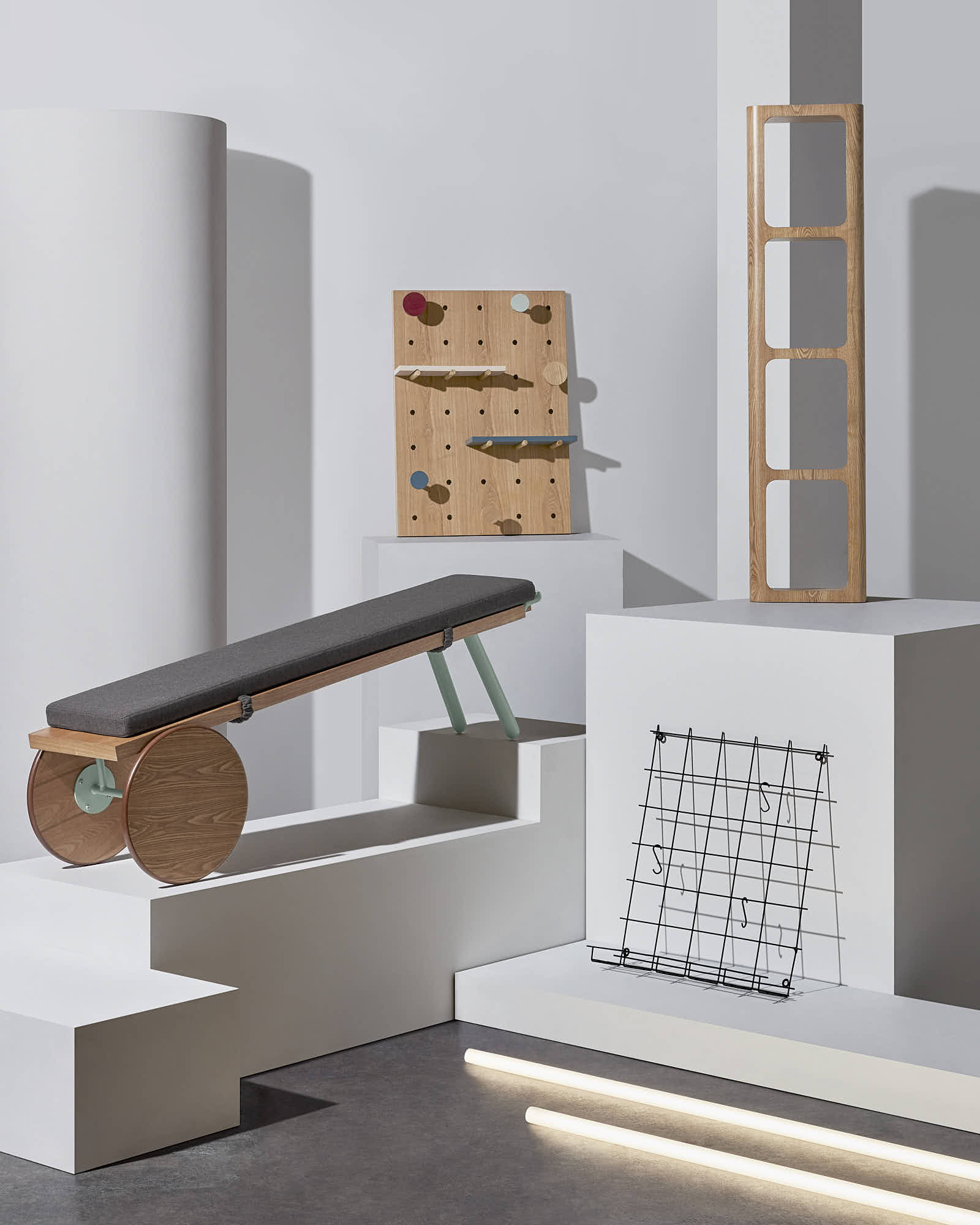Modern minimalist furniture display with wooden bench, pegboard, and geometric decor.