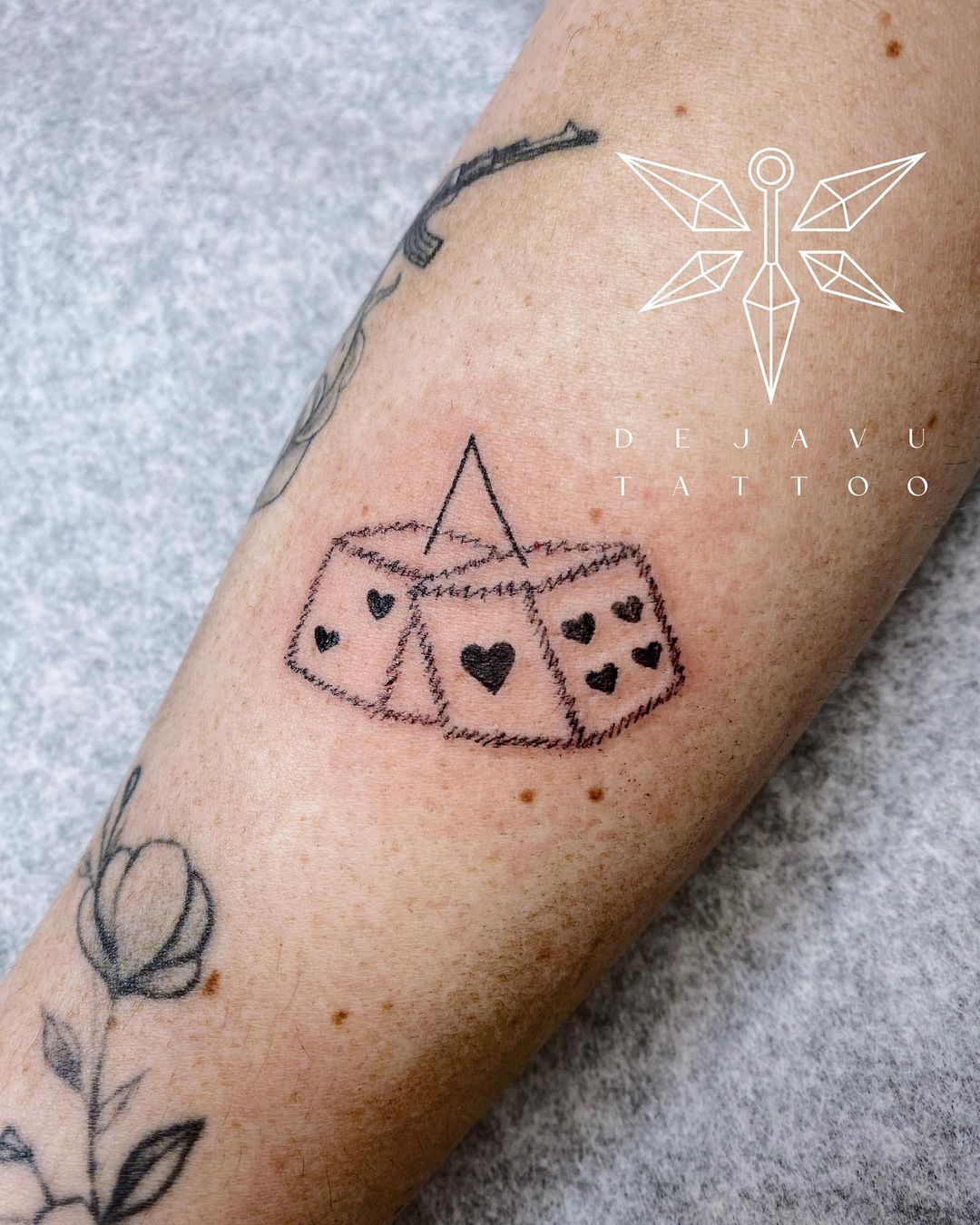 A new tattoo by Deja Vu Tattoo Co of a pair of dice hanging with hearts on each side