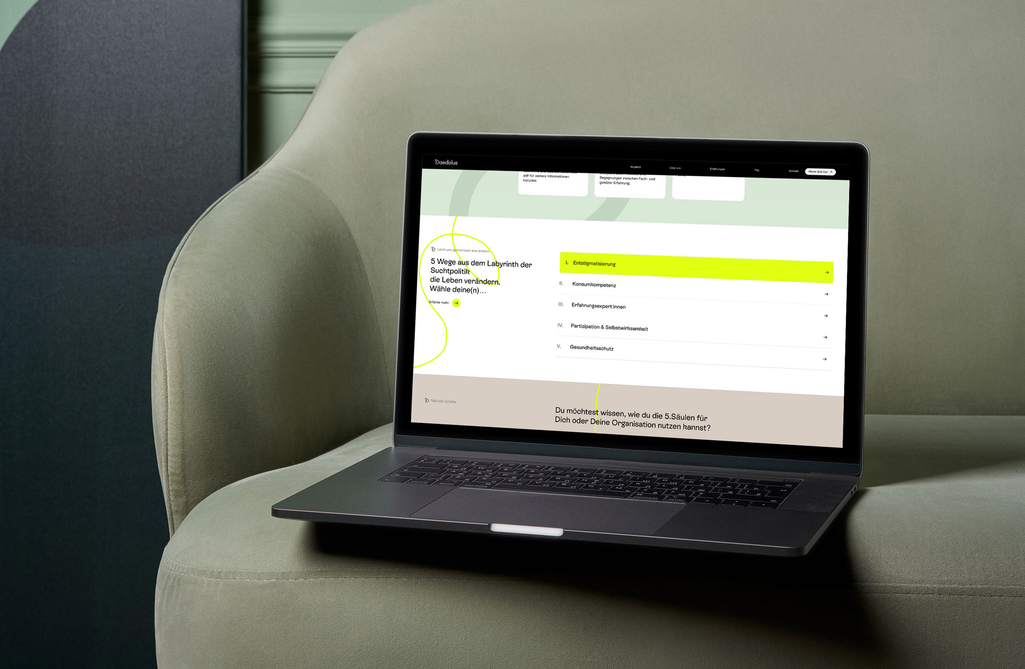 Laptop auf einem salbeigruenen Sofa mit Webdesign im Bildschirm