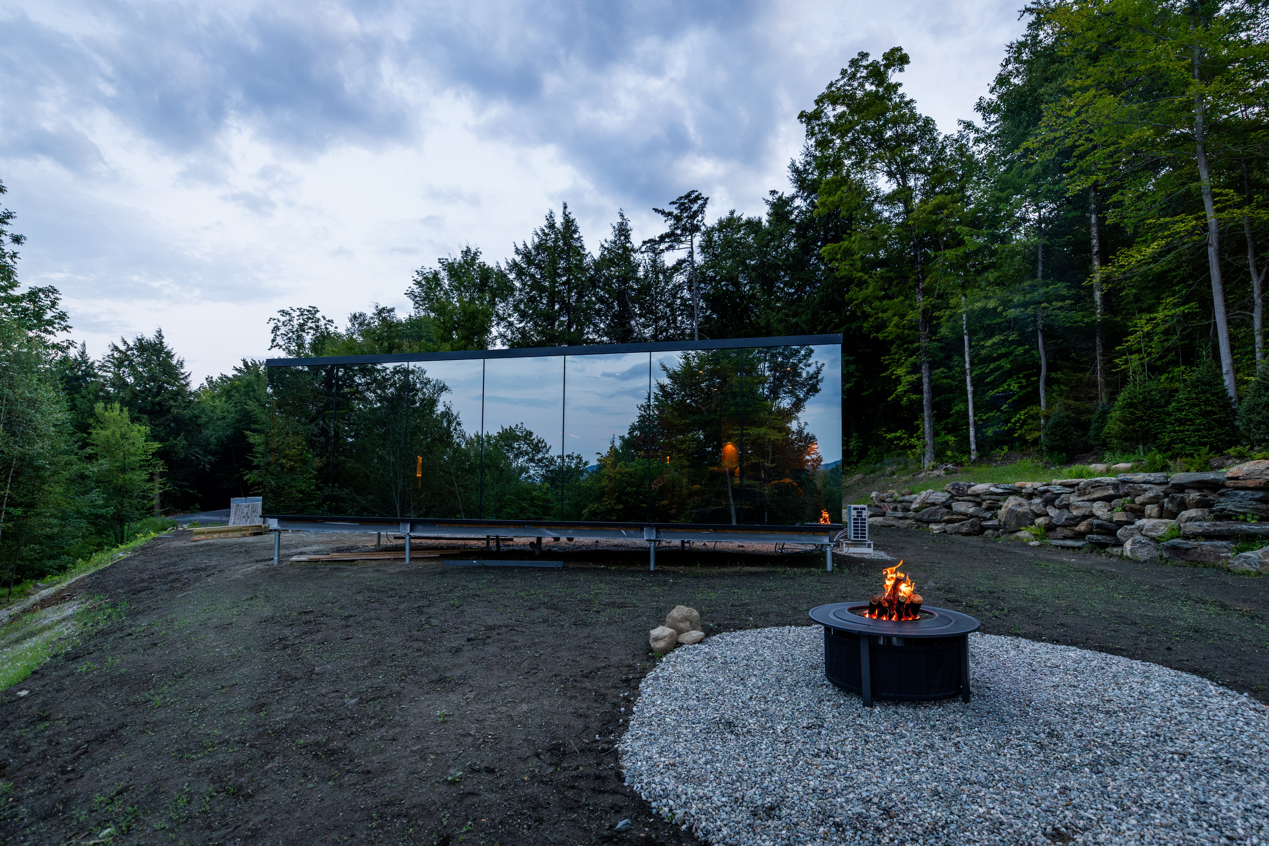 Mirrored cabin exterior with fire pit at dusk