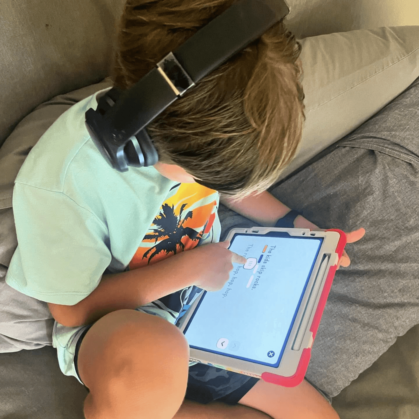 Image of a 7-year-old boy engaged in digital reading on his iPad using a reading app, enhancing his literacy skills through interactive technology. The boy's focused expression highlights the modern approach to learning to read, blending traditional literacy methods with innovative educational tools to foster a love for reading at a young age.